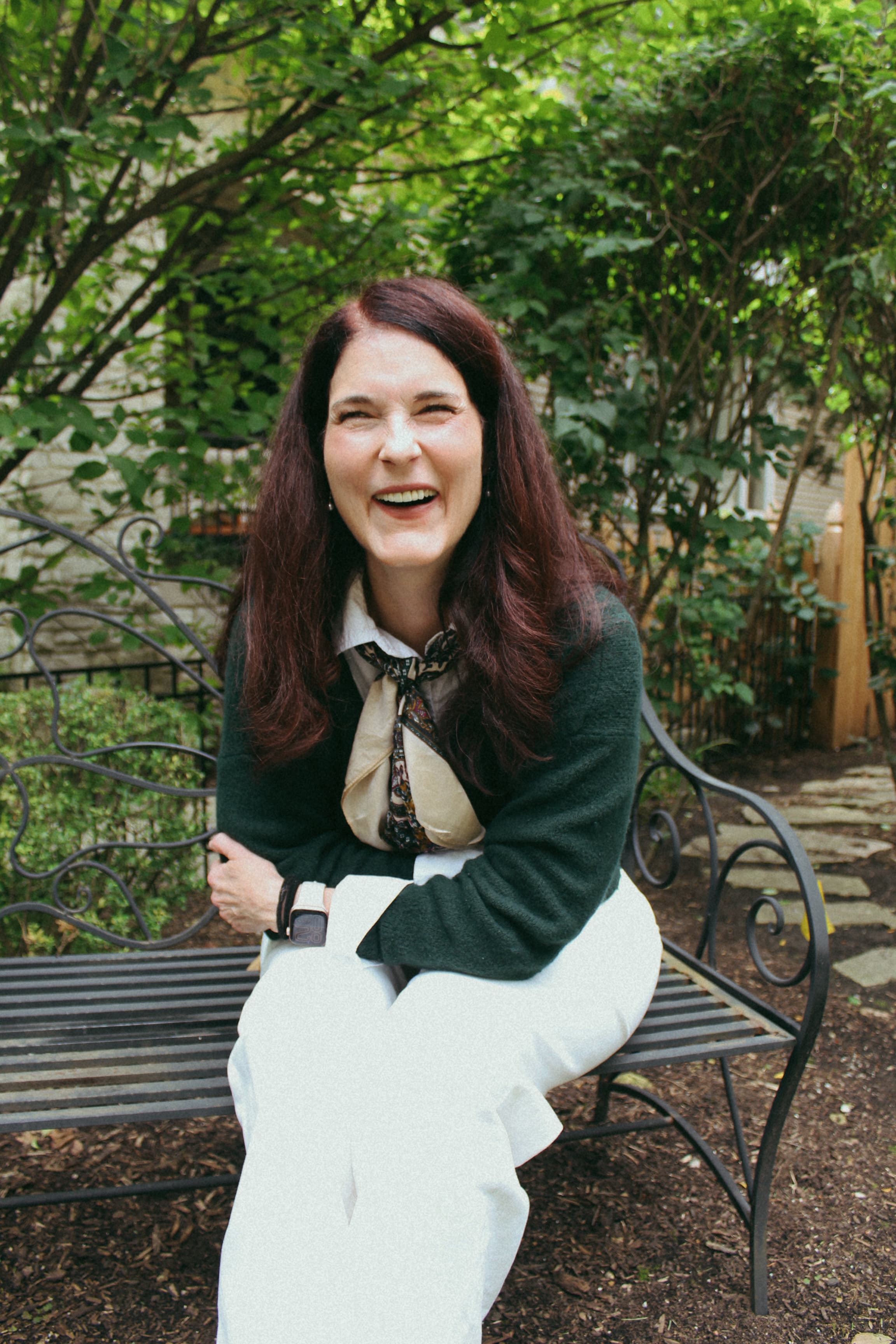 Abbie smiling while seated outside among green foliage