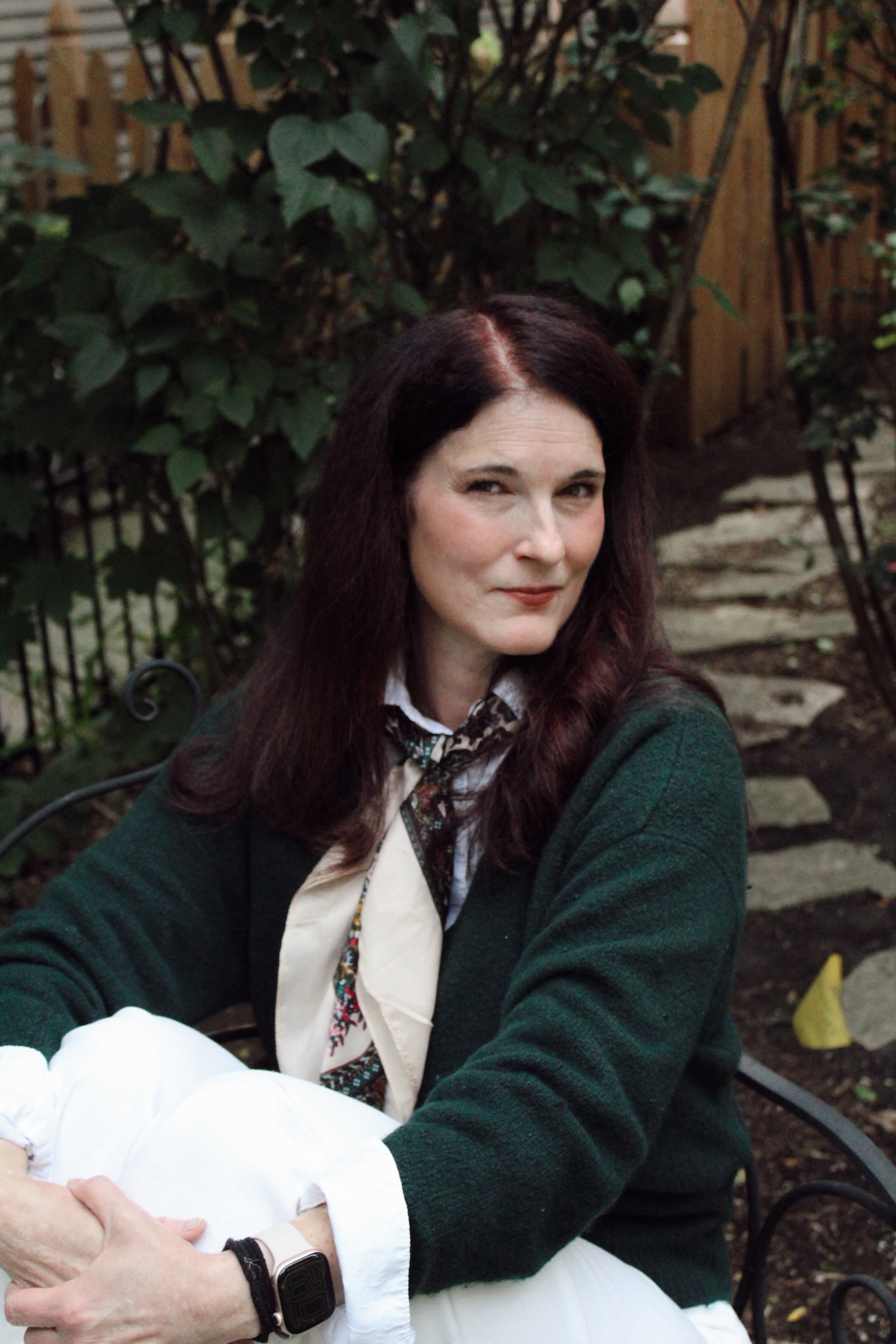 Abbie seated outside among green foliage