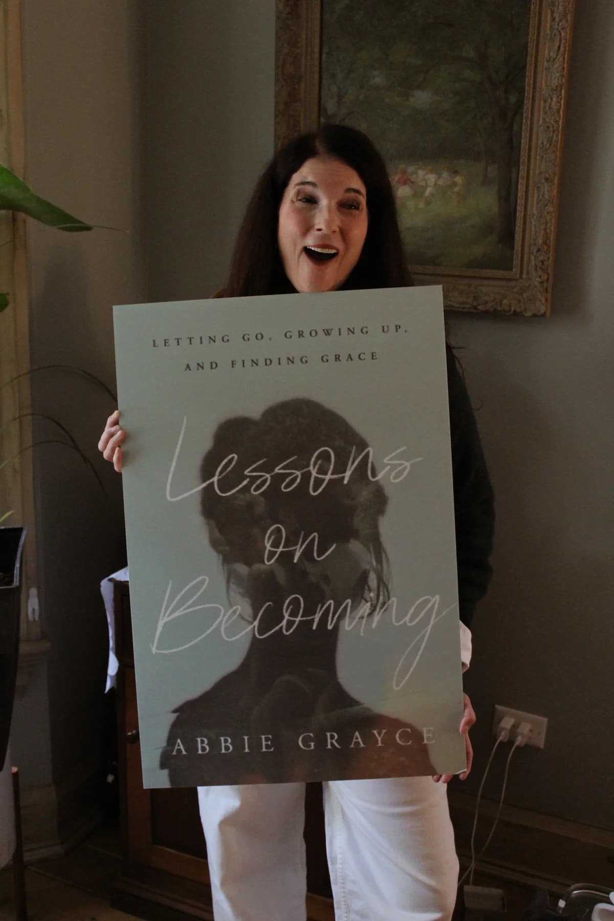 Abbie holding the complete printed cover of Lessons on Becoming